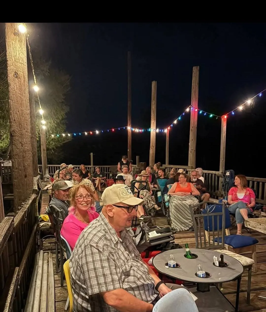 Friends gathered under string lights at night during TwisterFest at Muscle Car Ranch
