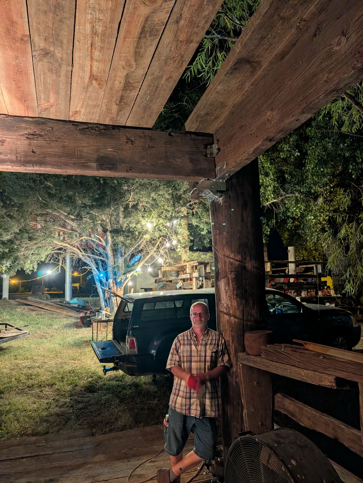 Crew member standing beneath the Heavy Chevy stage roof structure during nighttime construction at Muscle Car Ranch