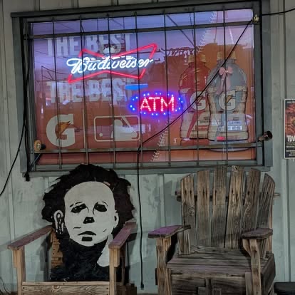 Vintage Budweiser and ATM neon signs in a rustic lounge area at Muscle Car Ranch in Chickasha, Oklahoma
