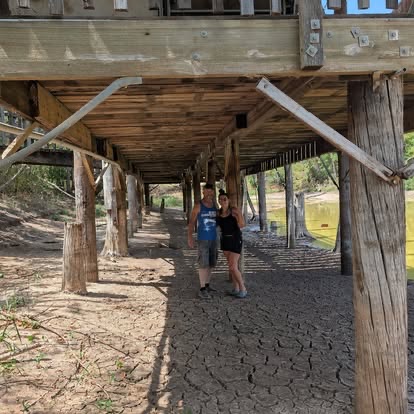 Volunteer walking beneath the long wooden venue structure during TwisterFest preparations at Muscle Car Ranch